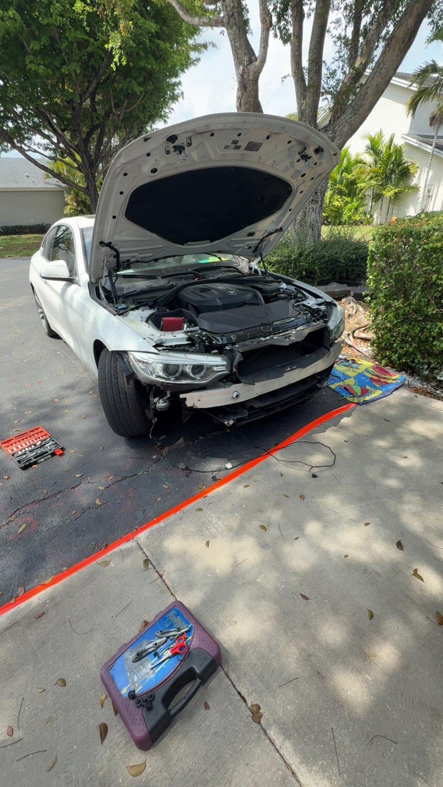 BMW with hood up during driveway repair work