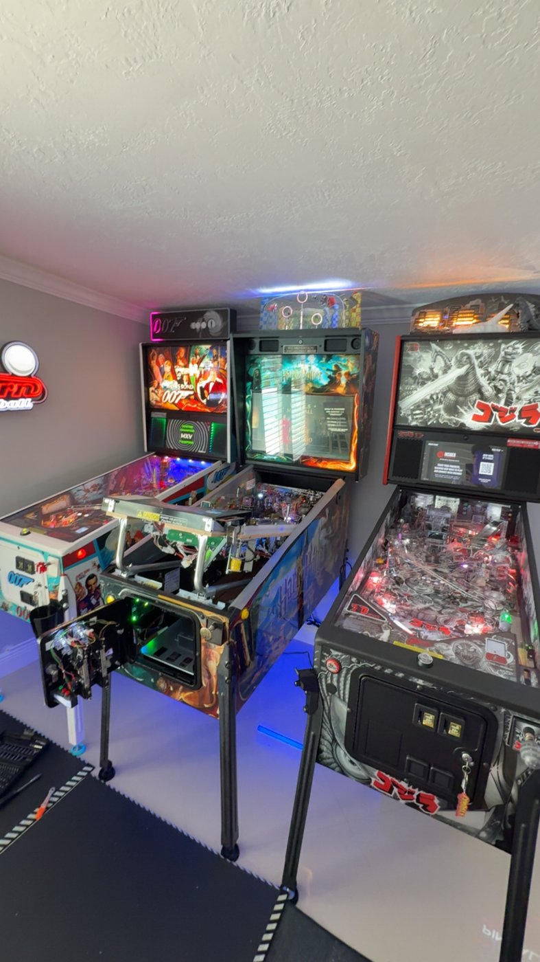 James Bond 007, Harry Potter, and Godzilla pinball machines in a private collector's game room